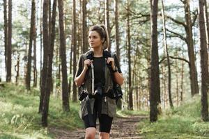 excursionista caminando con una mochila y una moderna cámara sin espejo en un bosque verde foto