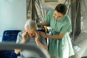 Young woman and senior man is feeling sick with migraine symptoms in public transport