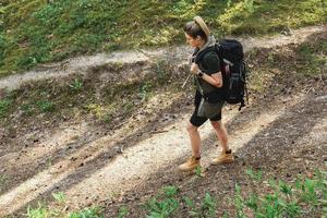 Female hiker with big backpack in green forest photo