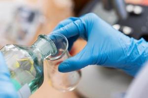 Scientist pouring substance from one flask to another in a laboratory photo