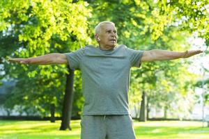 Elderly man exercising in green city park during his fitness workout photo