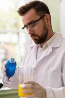 Scientist pouring water into the beaker in a laboratory during research photo