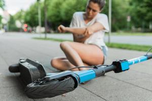 mujer joven que sufre de dolor en el codo después de un accidente de conducción en e-scooter foto