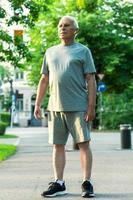 Elderly man during his jogging workout in a city park photo
