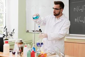 científico está vertiendo sustancia en el condensador en un laboratorio durante la investigación foto