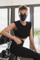 joven atlética que usa una máscara facial de prevención durante su entrenamiento de fitness.