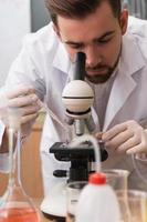 Scientist is using microscope in a laboratory during research photo