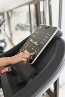 Woman changing settings on a treadmill in a gym photo