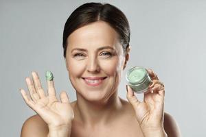 Beautiful middle aged woman with green mud mask photo