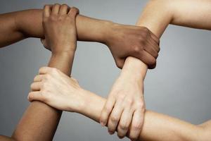 African and Caucasian female hands on gray background photo