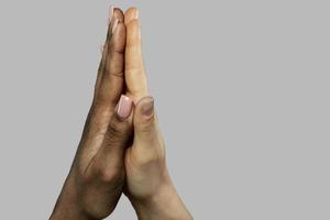 A high five gesture between African and Caucasian women. Closeup of palms on gray background. photo