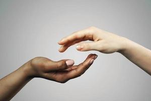 African and Caucasian female hands on gray background photo