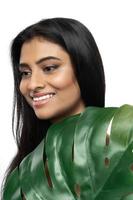 hermosa mujer india con una piel suave sosteniendo una hoja tropical verde foto