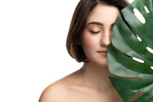 Portrait of young beautiful brunette woman with a monstera deliciosa tropical leaf photo