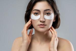 Beautiful woman with a smooth skin applying adhesive under-eyes patches for dark circles photo