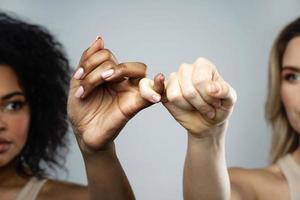 A pinky promise gesture between African and Caucasian women. photo