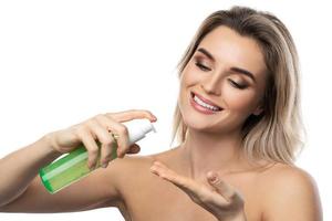 Young woman with a smooth skin holding a bottle of green cleansing gel photo