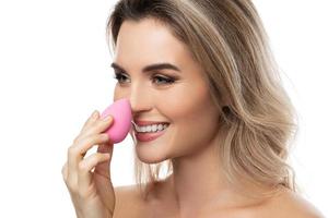 Beautiful woman with a smooth skin holding makeup sponge on white background photo