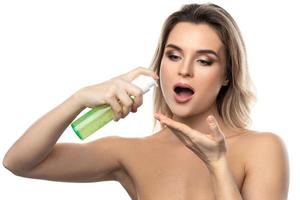 mujer joven con una piel suave sosteniendo una botella de gel limpiador verde foto