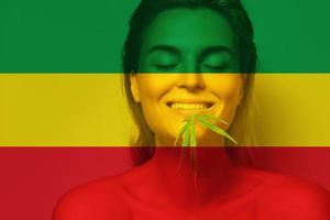 hermosa mujer con una hoja de cannabis en colores de la bandera rastafari foto