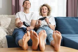 una pareja con gamepads está jugando una consola de videojuegos en casa foto
