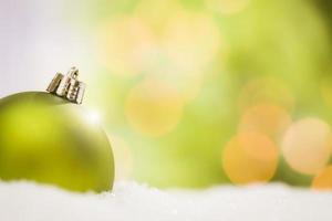 Green Christmas Ornaments on Snow Over an Abstract Background photo