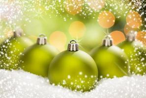 Green Christmas Ornaments on Snow Over an Abstract Background photo