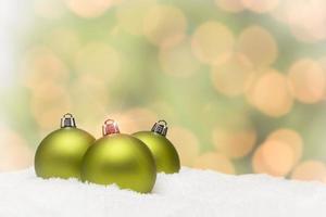 Green Christmas Ornaments on Snow Over an Abstract Background photo