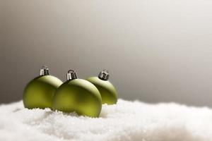 Green Christmas Ornaments on Snow Over a Grey Background photo