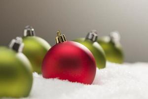 Red and Green Christmas Ornaments on Snow Over Grey photo