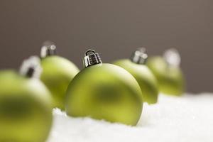Green Christmas Ornaments on Snow Over a Grey Background photo