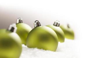 Green Christmas Ornaments on Snow Over a Grey Background photo