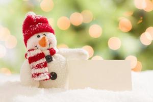 Cute Snowman with Blank White Card Over Abstract Background photo