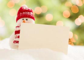 Cute Snowman with Blank White Card Over Abstract Background photo