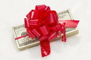 Stack of Hundred Dollar Bills with Red Ribbon on Snow photo