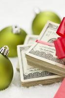 Stack of Hundred Dollar Bills with Bow Near Christmas Ornaments photo