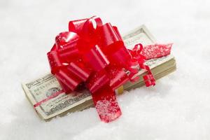 Stack of Hundred Dollar Bills with Red Ribbon on Snow photo