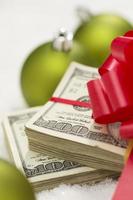 Stack of Hundred Dollar Bills with Bow Near Christmas Ornaments photo