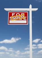 Left Facing Sold For Sale Real Estate Sign on a Blue Sky with Clouds. photo