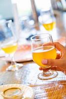 Female Hand Holding Glass of Micro Brew Beer At Bar photo