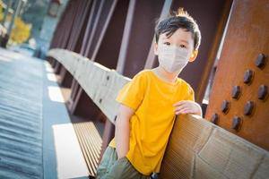 Young Mixed Race Chinese and Caucasian Boy Playing Alone Wearing Medical Face Mask Outside photo