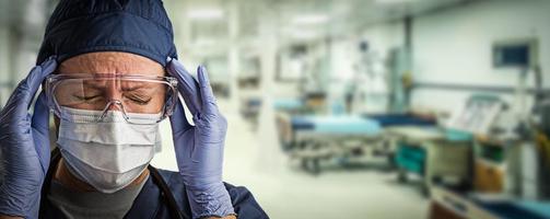 Stressed Doctor or Nurse Wearing Medical Personal Protective Equipment Within Hospital. photo