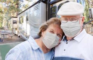 Senior Couple Wearing Medical Face Masks In Front of Their Beautiful RV At The Campground. photo