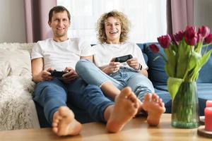 una pareja con gamepads está jugando una consola de videojuegos foto