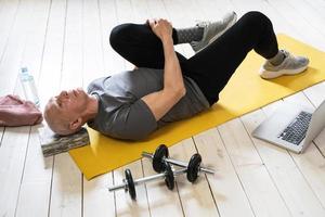 anciano activo estirándose durante su entrenamiento de fitness en casa foto