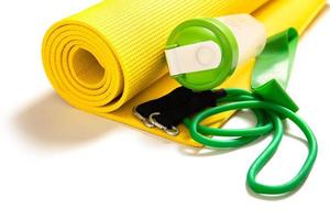 Protein shaker, fitness mat and rubber resistance bands on white background photo