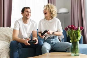 Couple with a gamepads are playing video game console at home photo