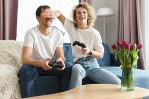 una pareja con gamepads está jugando una consola de videojuegos en casa foto