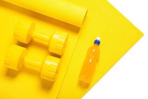 Yellow dumbbells, fitness mat and orange electrolyte drink photo