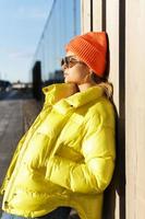 Stylish girl wearing yellow puffer and orange knitted hat photo